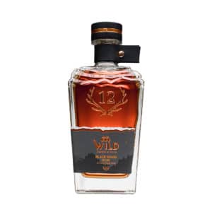 Eine Flasche Black Wood Rum mit klarem Glasdesign, Kupferakzenten und einem dunklen Etikett mit Geweih und Berggrafiken.