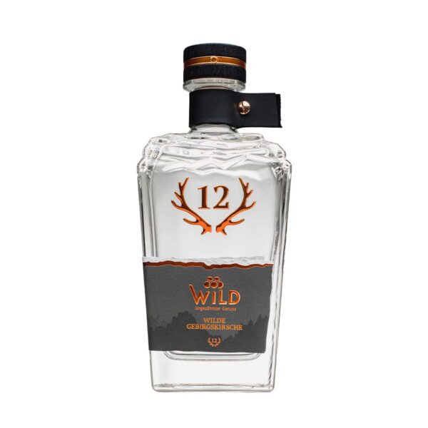 Eine Klarglasflasche mit der Aufschrift Wilde Gebirgskirsche mit Geweihgrafik, einem schwarz-kupferfarbenen Verschluss und einem grauen Etikett. Die Flasche enthält eine klare Flüssigkeit.