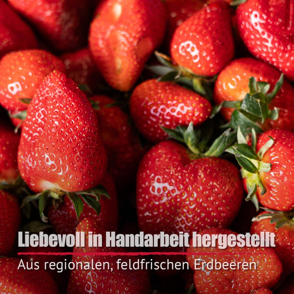 Nahaufnahme von frischen Erdbeeren mit deutschem Text überlagert: "Erdbeer-Limes - liebevoll in Handarbeit hergestellt aus regionalen, feldfrischen Erdbeeren.