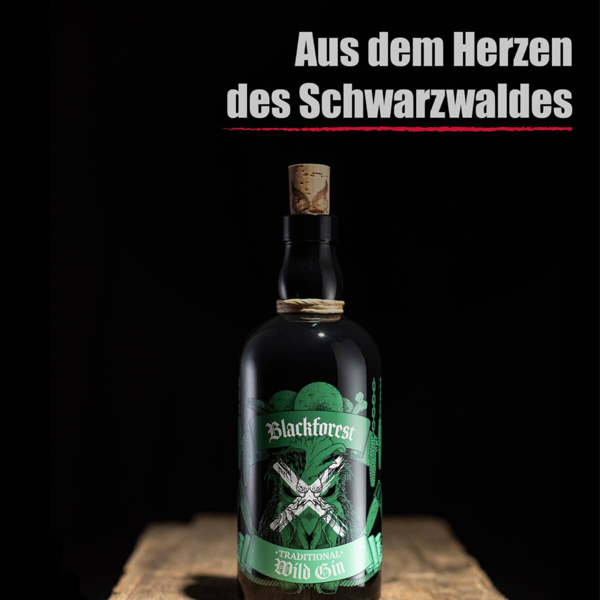 Eine Flasche Blackforest Wild Gin Traditional steht auf einer hölzernen Fläche mit dem deutschen Text "Aus dem Herzen des Schwarzwaldes" darüber.