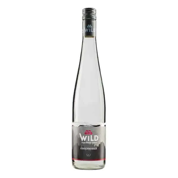 Eine Klarglasflasche mit Wildkirschwasser mit silbernem Verschluss und Etikett, die eine transparente Spirituose enthält.