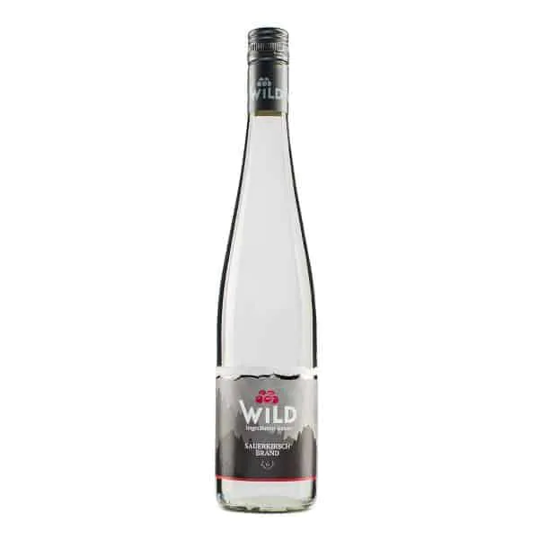 Eine Klarglasflasche der Marke Wild Sauerkirsch mit einem silbernen Schraubverschluss und einem grauen Etikett mit Kirschen und Berggrafiken.
