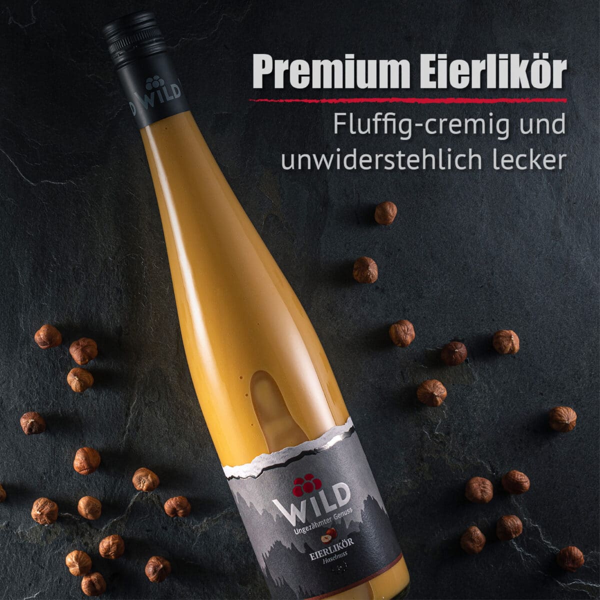Eine Flasche Eierlikör Haselnuss ruht auf einer dunklen Steinfläche, umgeben von Haselnüssen, und ein deutscher Text hebt die cremige, flauschige Textur und den unwiderstehlich köstlichen Geschmack hervor.