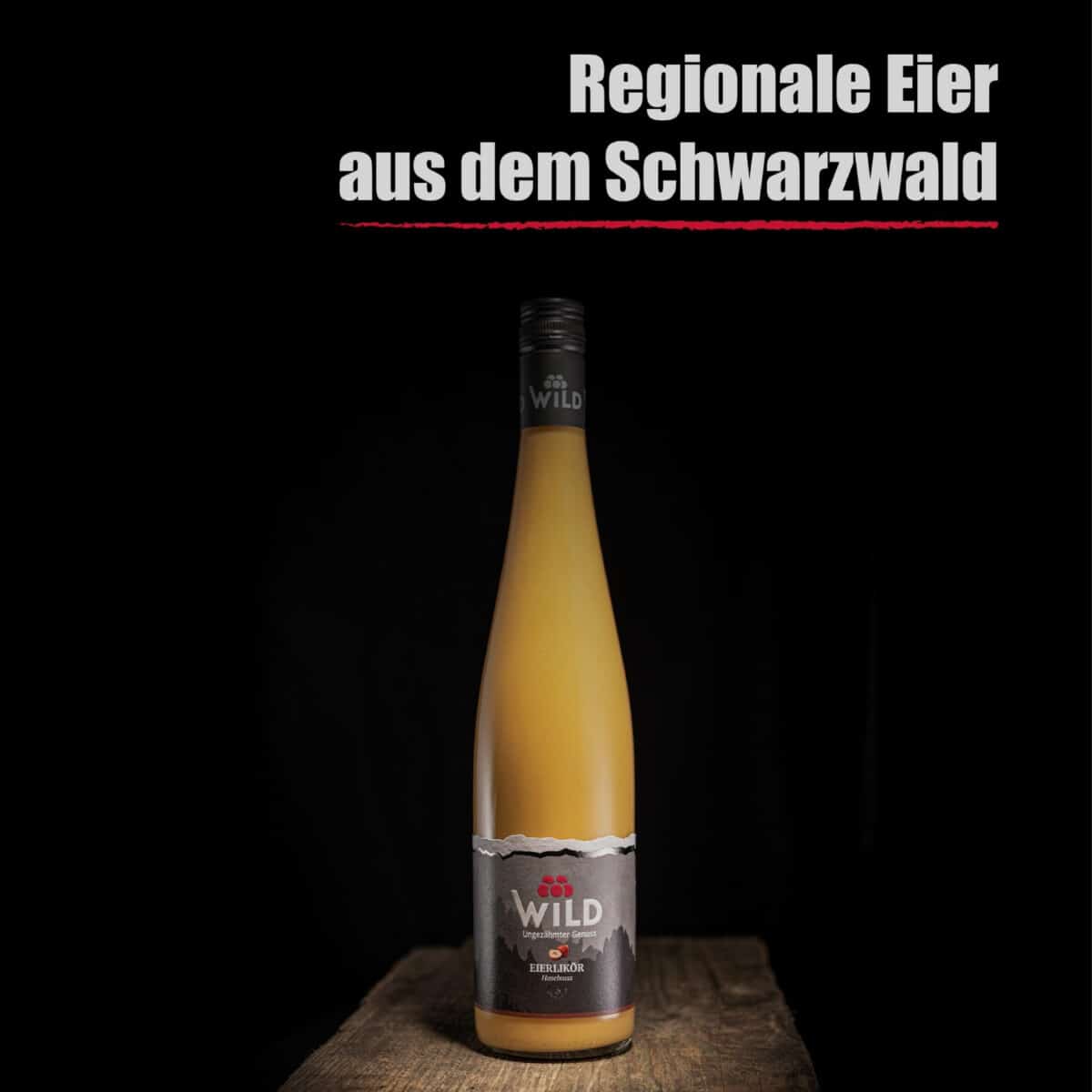 Eine hohe Flasche mit der Aufschrift "Eierlikör Haselnuss" steht auf einer hölzernen Unterlage, darüber auf schwarzem Hintergrund der Text "Regionale Eier aus dem Schwarzwald".