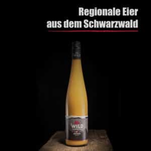 Eine hohe Flasche mit der Aufschrift "Eierlikör Haselnuss" steht auf einer hölzernen Unterlage, darüber auf schwarzem Hintergrund der Text "Regionale Eier aus dem Schwarzwald".