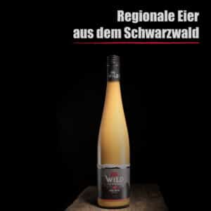 Eine Flasche Eierlikör Himbeere steht auf einer hölzernen Oberfläche mit dem deutschen Text Regionale Eier aus dem Schwarzwald darüber auf schwarzem Hintergrund.