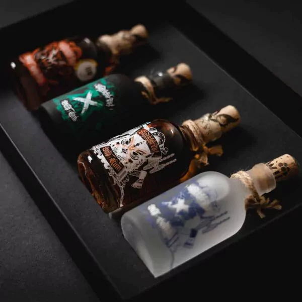 Die Blackforest Wild Spirits all in (0,2) mit Geschenketui besteht aus vier kleinen Glasflaschen mit illustrierten Etiketten und Korkstopfen, die jeweils mit einer andersfarbigen Spirituose gefüllt sind und in einer schwarzen Geschenkbox verpackt sind.