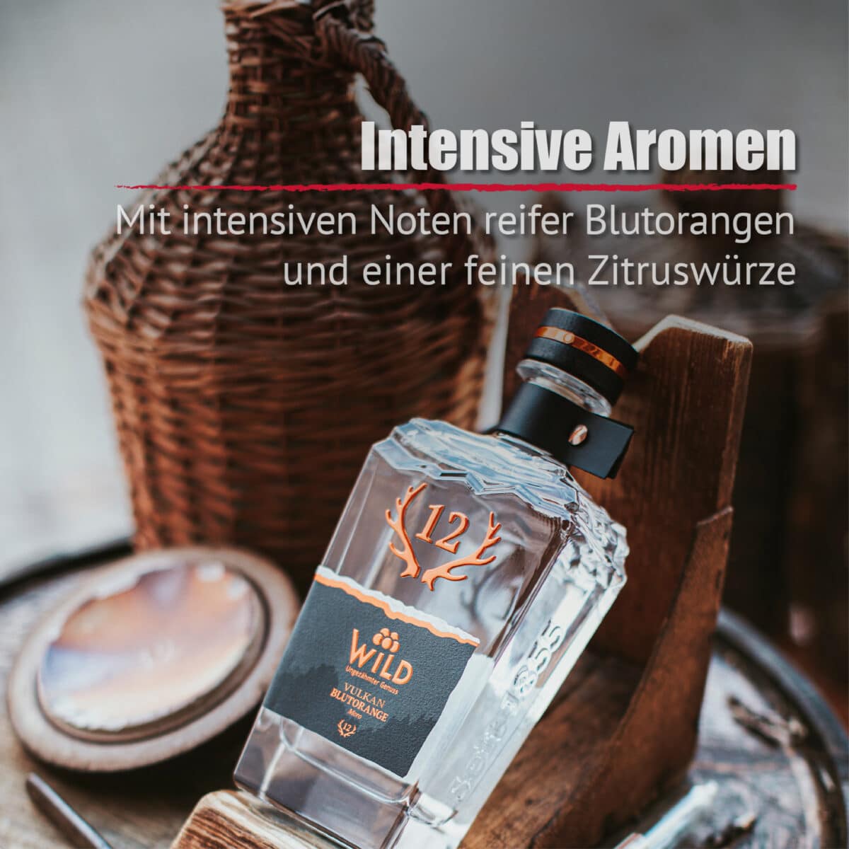 Eine Flasche Vulkan Blutorange Moro Gin steht auf einer hölzernen Oberfläche neben einem Weidenkorb und einer Kupferkelle. Der Text darüber hebt das kräftige Aroma und die lebhaften Zitrusnoten hervor.