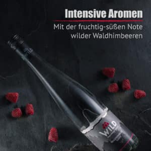 Eine Flasche Waldhimbeergeist ruht auf einer dunklen Fläche mit verstreuten Himbeeren, die das intensive Aroma der Waldhimbeere hervorheben, wie im deutschen Text beschrieben.