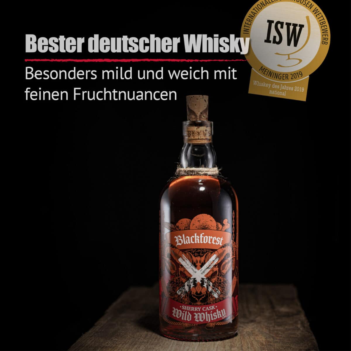 Eine Flasche Blackforest Wild Whisky Sherry Cask mit Korkverschluss steht auf Holz und ist mit einem rot-schwarzen Etikett, einer Medaille und einem deutschen Text versehen, der seinen milden, fruchtigen Geschmack hervorhebt.
