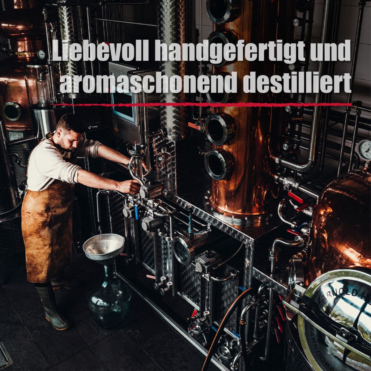 Ein Mann in einer Schürze bedient eine Destillationsmaschine in einer Industrieanlage; der deutsche Text lautet "In liebevoller Handarbeit und schonend destilliert" für Wilde Vogelbeere.