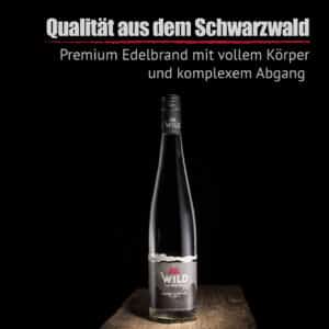 Eine Flasche Zibärtle Wildpflaumenbrand steht auf einer hölzernen Oberfläche vor einem schwarzen Hintergrund, auf dem ein deutscher Text über die außergewöhnliche Qualität des Schwarzwaldes steht.