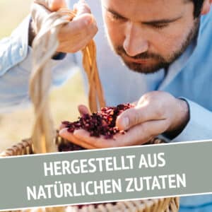 Ein Mann riecht an getrockneten Kräutern in einem Korb neben dem deutschen Text HERGESTELLT AUS NATÜRLICHEN ZUTATEN, der die natürliche Essenz von LÚVO Hibiskus x Basilikum - Alkoholfrei hervorhebt, das auf dem Bild zu sehen ist.