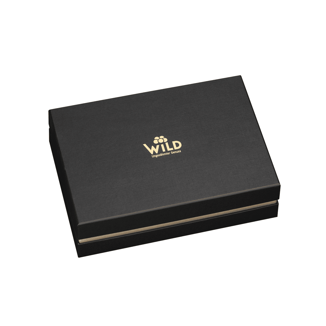 Die Premium Blackforest Wild Spirits Tastingbox ist eine geschlossene, schwarze, rechteckige Geschenkbox mit dem Schriftzug WILD" und einem goldenen Blumenlogo auf dem Deckel vor weißem Hintergrund - ideal, um ein einzigartiges Verkostungserlebnis zu teilen.