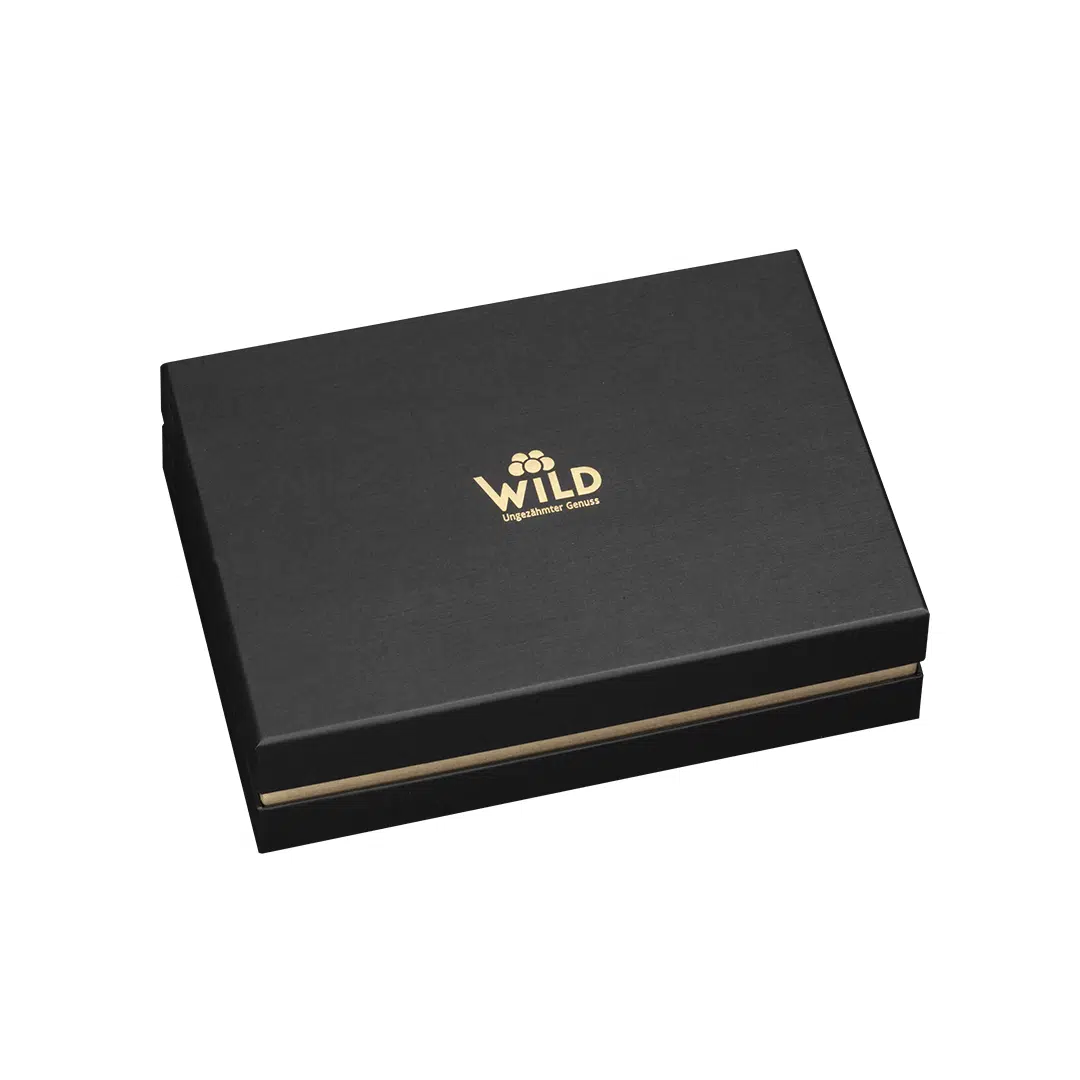 Die Premium Blackforest Wild Spirits Tastingbox ist eine geschlossene, schwarze, rechteckige Geschenkbox mit dem Schriftzug WILD" und einem goldenen Blumenlogo auf dem Deckel vor weißem Hintergrund - ideal, um ein einzigartiges Verkostungserlebnis zu teilen.